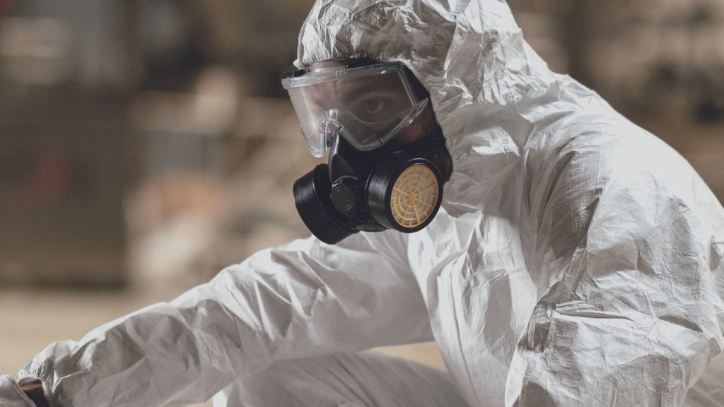 Arbeiter mit CSA Chemieschutzanzug mit E.COOLINE Kühlkleidung darunter und Atemschutzmaske knieend