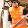 Bauarbeiter trägt Kühlweste SX3 mit Reflektoren von E.COOLINE in Farbe Signalorange