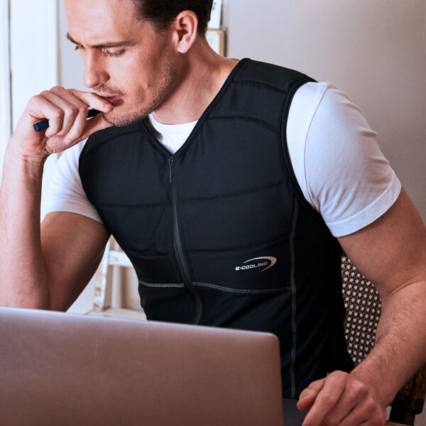 Mann trägt Kühlshirt von E.COOLINE in Farbe schwarz und arbeitet am Laptop