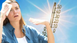 Frau mit Hitzeproblemen in der Sonne mit Temperaturanzeige